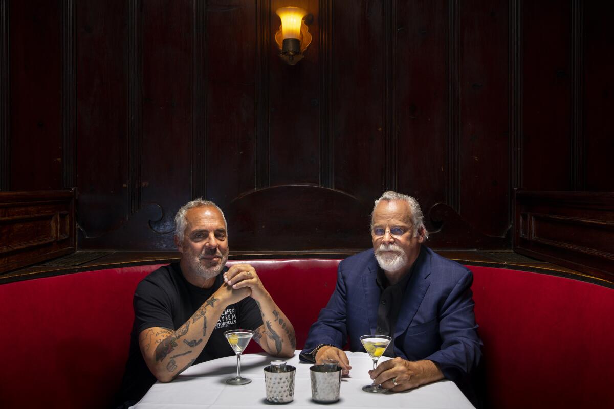 Two men with martinis in a red leather restaurant booth