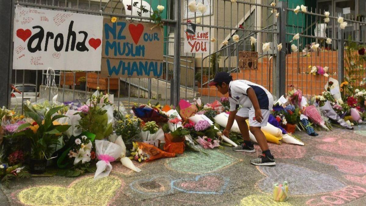 A boy places flowers outside a mosque in Wellington, New Zealand. At least 49 people were killed Friday in attacks on two mosques in Christchurch.