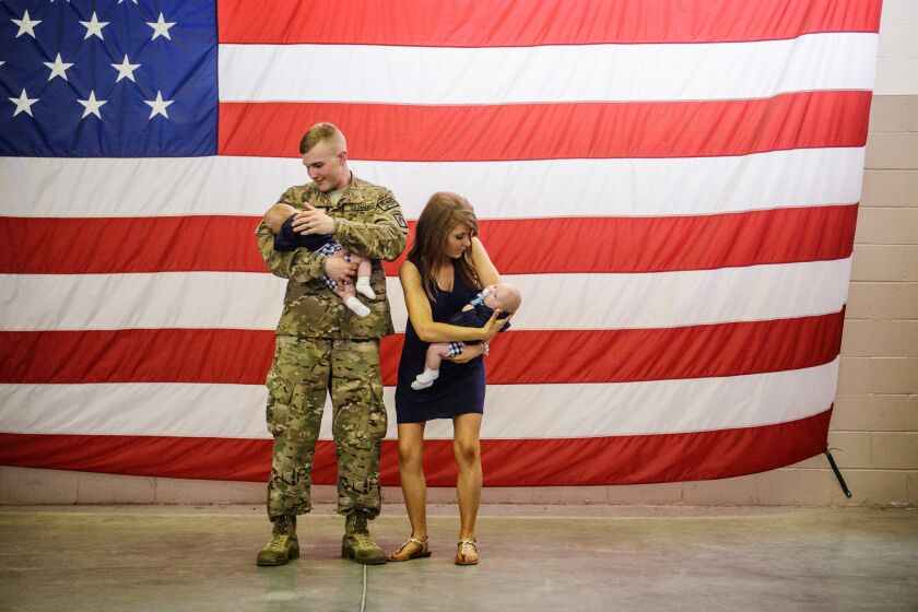 Spc. Aaron Schade and his wife, Amanda, prepare to be photographed with their twin boys upon his return to North Carolina from Afghanistan in July 2014.