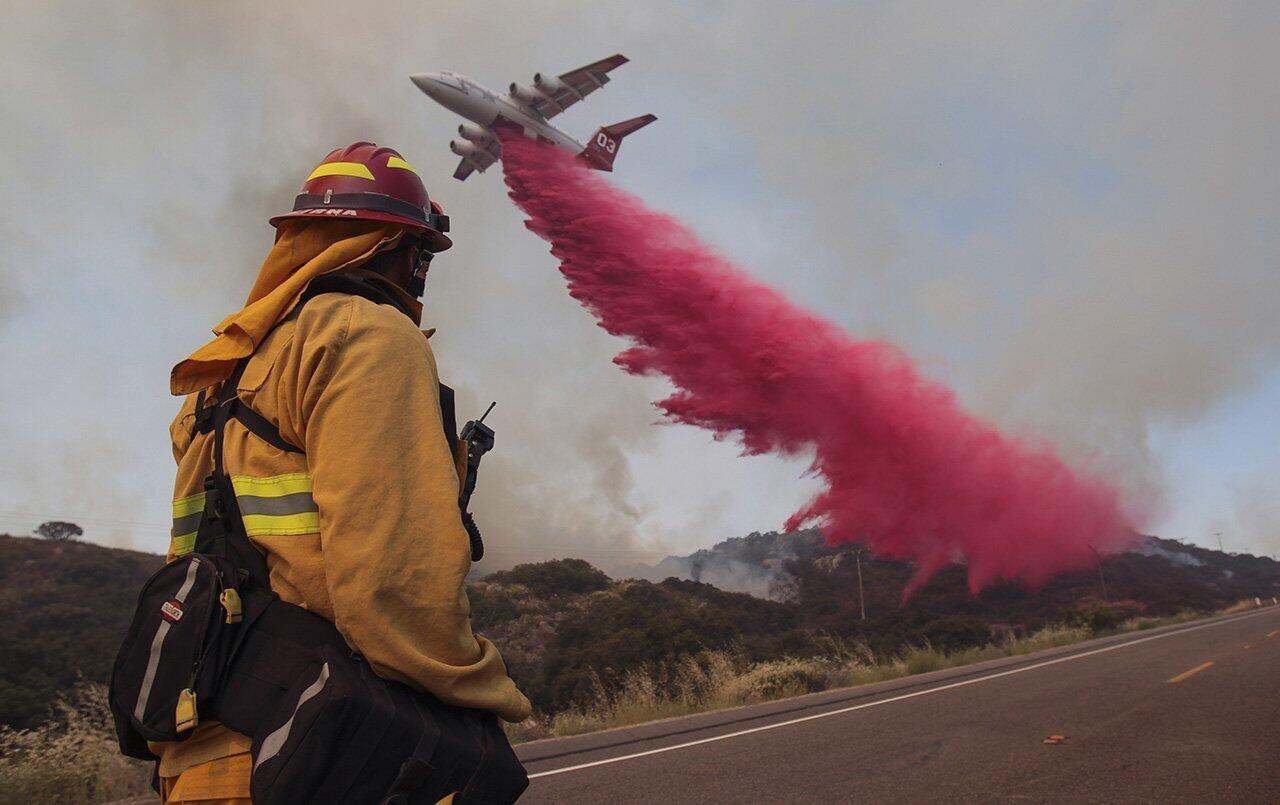 Upland Fire Capt. Joe Burna watches as a tanker drops fire retardant to stop a wildfire from jumping over Highway 94 near Potrero on Monday.