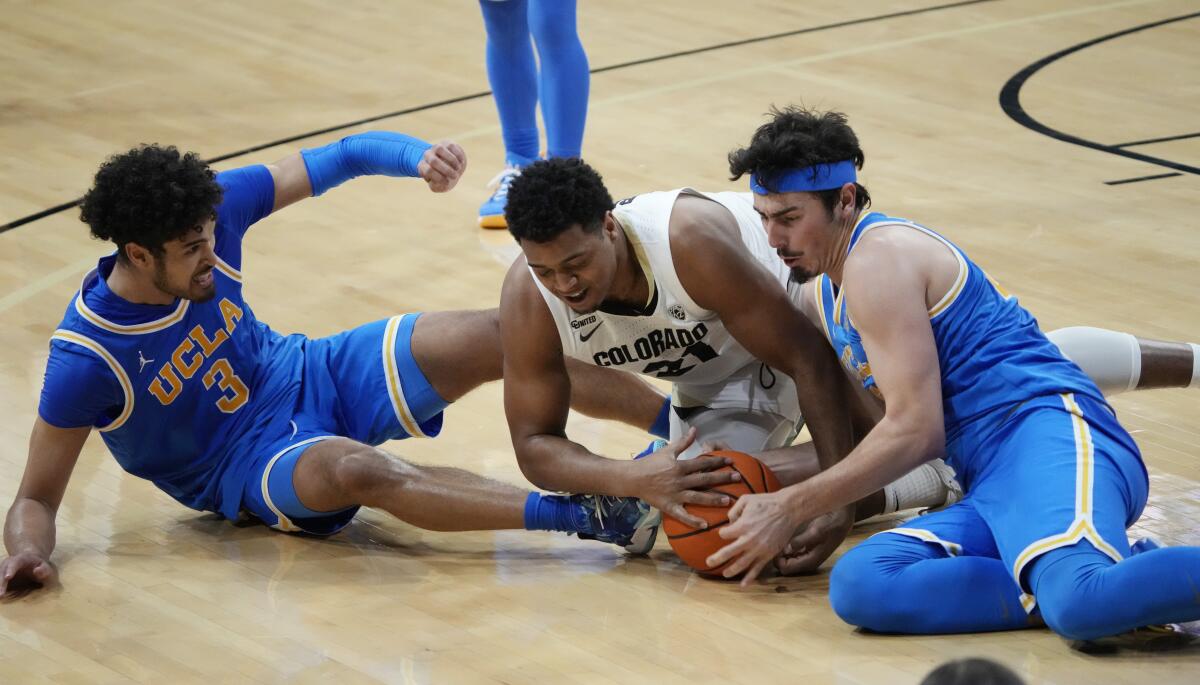 UCLA guards Jaime Jaquez Jr., right, and Johnny Juzang hit the floor battling Colorado forward Evan Battey for the ball