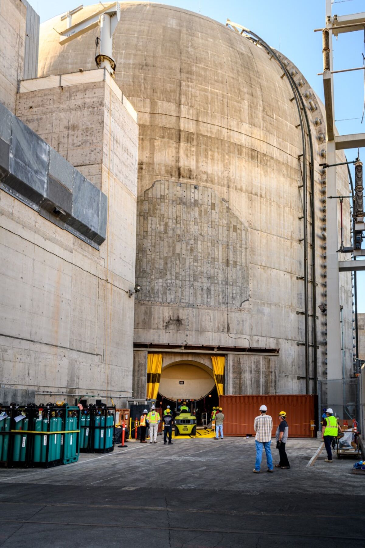 Workers and equipment in an open hatchway at the base of a nuclear plant containment dome