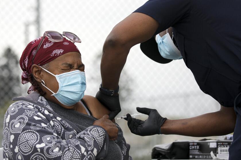 Los Angeles, CA - February 09: LA City firefighter Dion Cooper, right, administers a COVID-19 vaccine to Marilyn Shugars,71, at a mobile vaccination site launched by Los Angeles Councilman Curren Price Jr. at South Park Recreation Center on Tuesday, Feb. 9, 2021 in Los Angeles, CA.(Irfan Khan / Los Angeles Times)