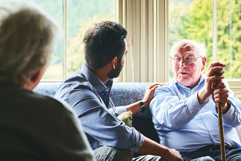 Healthcare worker talking with senior male patient at home
