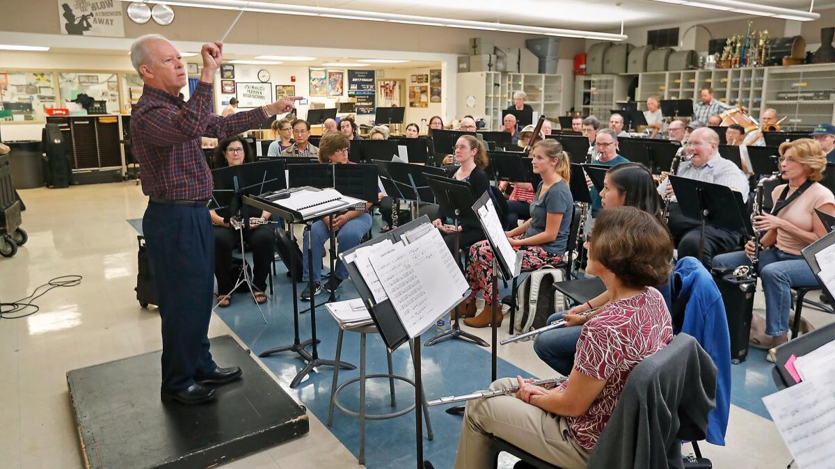 Music director Tom Ridley leads the Huntington Beach Concert Band during a rehearsal at Marina High School in Huntington Beach on Tuesday in preparation for a concert celebrating his 40-year service to the group.