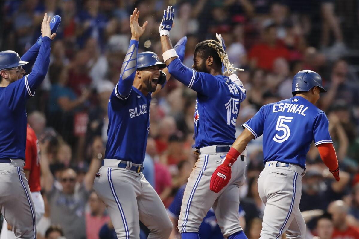 Toronto Blue Jays' Raimel Tapia (15) celebrates his inside-the-park grand slam that scored Lourdes Gurriel Jr., center left, Danny Jansen, left, and Santiago Espinal (5) during the third inning of the team's baseball game against the Boston Red Sox, Friday, July 22, 2022, in Boston. (AP Photo/Michael Dwyer)