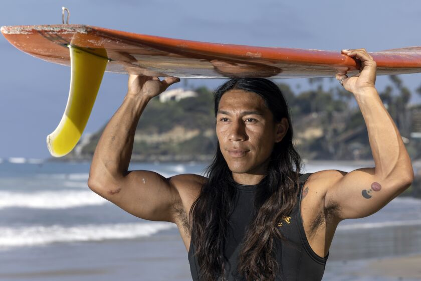 ENCINITAS CA - AUGUST 25, 2022: Mario Ordonez-Calderon, who is the executive director and co-founder of Un Mar de Colores, An Ocean of Colors, with his surfboard at San Elijo State Beach in Cardiff on Thursday, August 25, 2022. (Hayne Palmour IV / For The San Diego Union-Tribune)