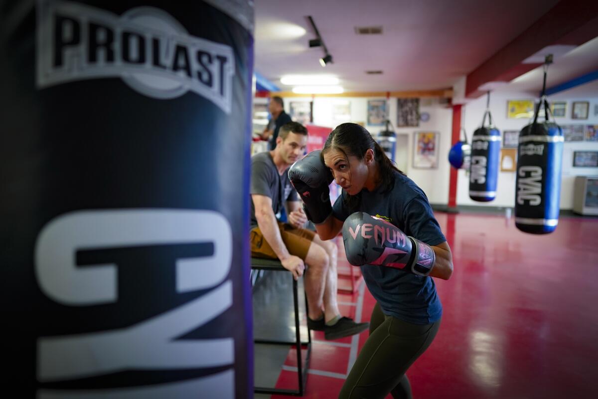 Jen Pitassi works out on the heavy bag with her husband Ben Pitassi observing at the Community Youth Athletic Center.