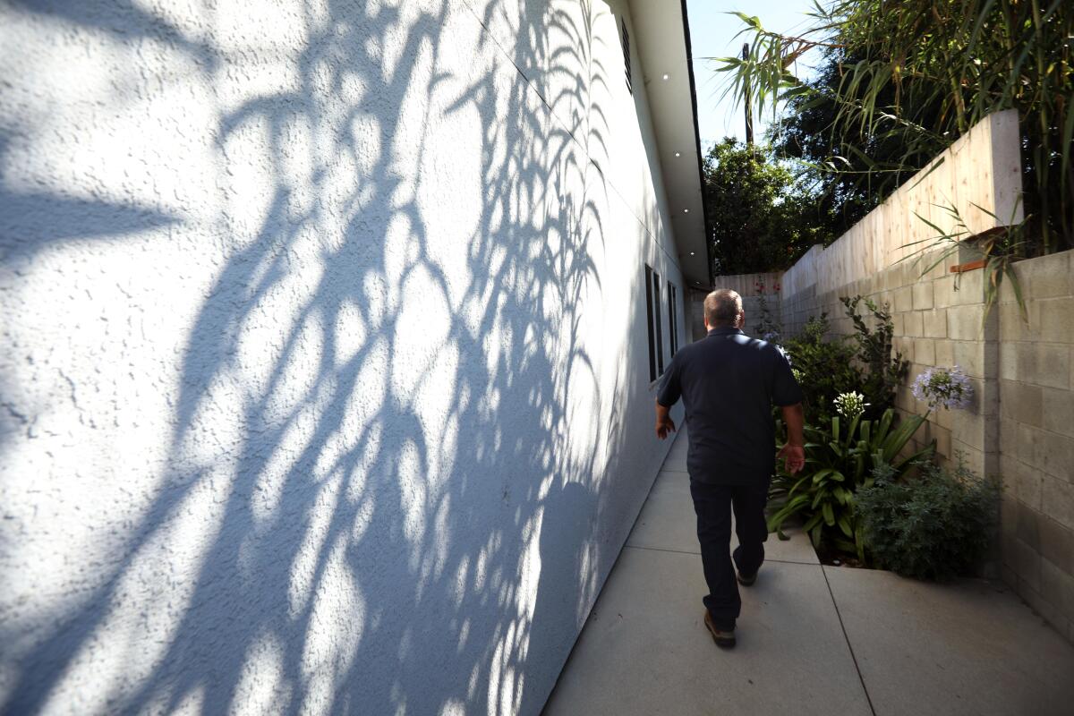 Hector Lopez walks outside an ADU he built for his daughter.