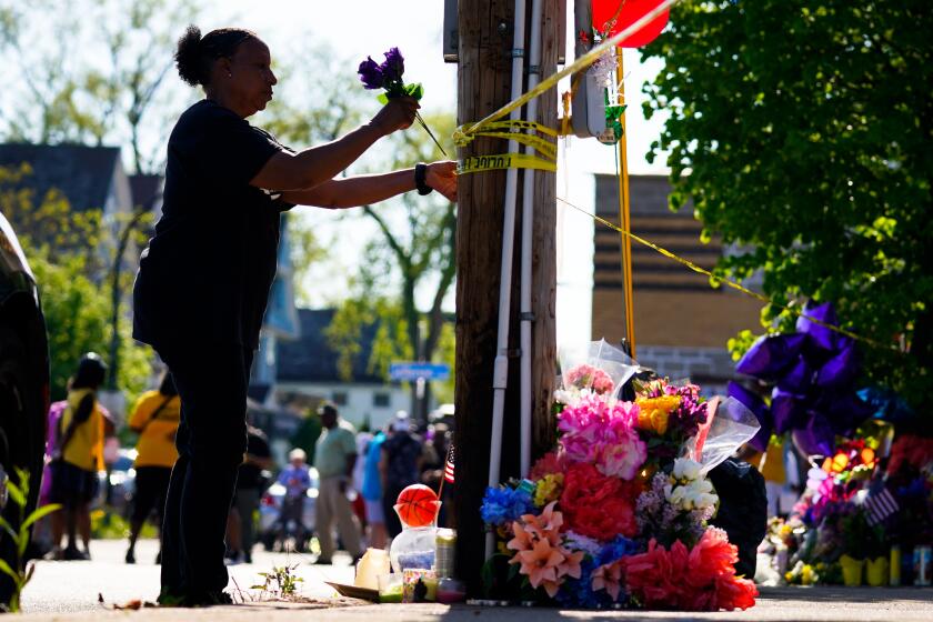 A person tends to a makeshift memorial outside the scene of a shooting at a supermarket the day before, in Buffalo, N.Y., Sunday, May 15, 2022. (AP Photo/Matt Rourke)