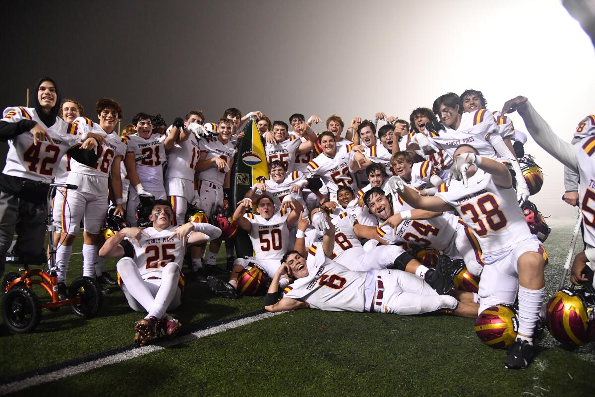 The Torrey Pines football team celebrates with the surfboard.