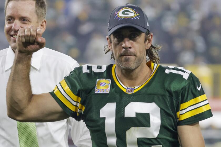 FILE - Green Bay Packers' Aaron Rodgers smiles as he leaves the field after an NFL football game against the Pittsburgh Steelers Sunday, Oct. 3, 2021, in Green Bay, Wis. Pro athletes who have refused to be vaccinated have been put at center court in a larger contest, as proxy players in the cultural battles over COVID jabs. (AP Photo/Mike Roemer, File)