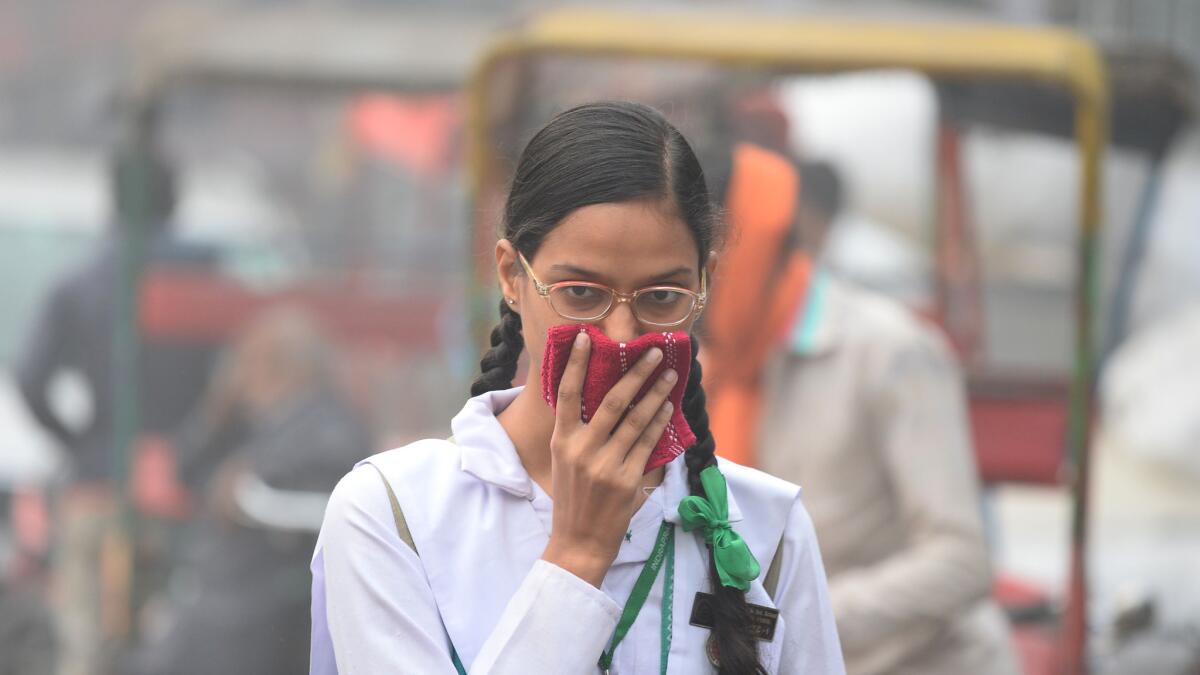 An Indian schoolgirl covers her face with a handkerchief amid heavy smog in New Delhi.