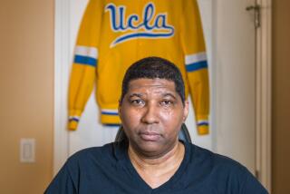 Former UCLA basketball star Rod Foster holds a basketball and sits in his wheelchair in his West L.A. home. 