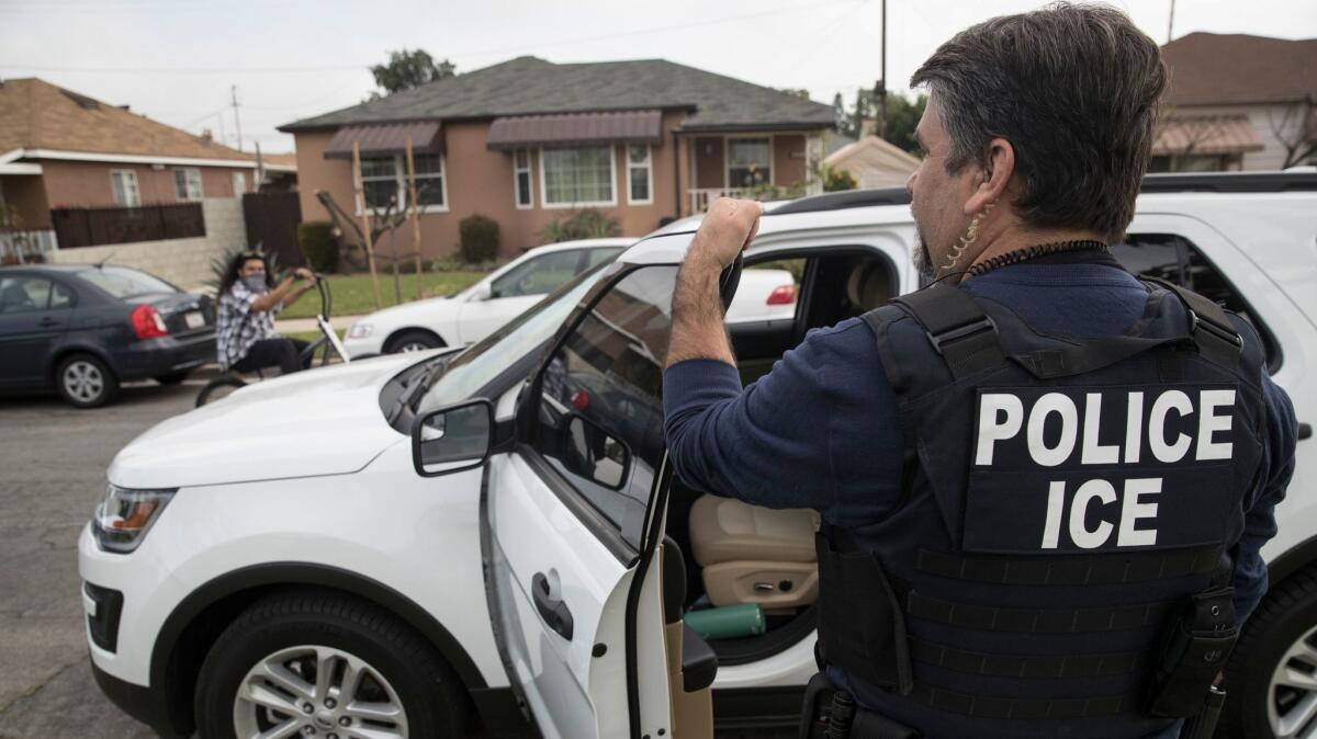 Jorge Field, agente de ICE, espera afuera de un hogar en Montebello el 18 de abril. El agente, junto con otros oficiales, prepara el arresto de un hombre de origen mexicano de 47 años. (Brian van der Brug / Los Angeles Times)