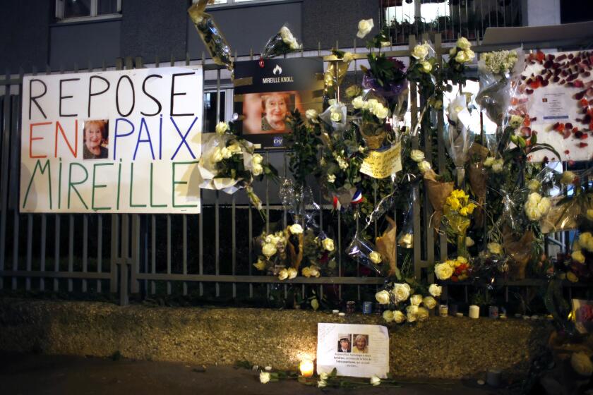 Flowers and placards are displayed outside Mireille Knoll's apartment during a silent march on March 28, 2018 in Paris. A French man was sentenced to life in prison for stabbing an 85-year-old Holocaust survivor to death in an antisemitic attack, according to the victim's son. The killing of Mireille Knoll in 2018 prompted widespread outrage and called attention to resurgent anti-Jewish sentiment and violence in France. (AP Photo/Thibault Camus, file)