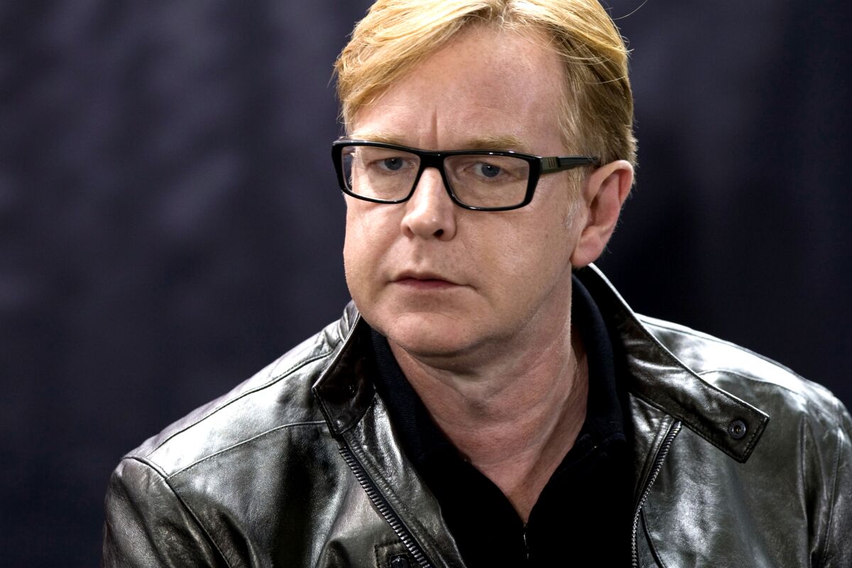 A middle-aged man with blond hair, wearing glasses and a leather jacket