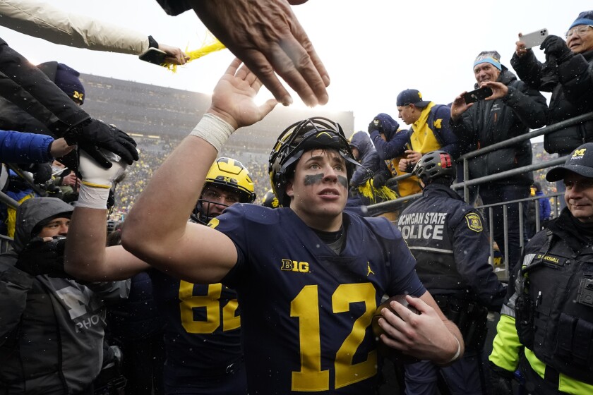Michigan quarterback Cade McNamara greets fans as he exits the field after the second half of an NCAA college football game against Ohio State, Saturday, Nov. 27, 2021, in Ann Arbor, Mich. (AP Photo/Carlos Osorio)