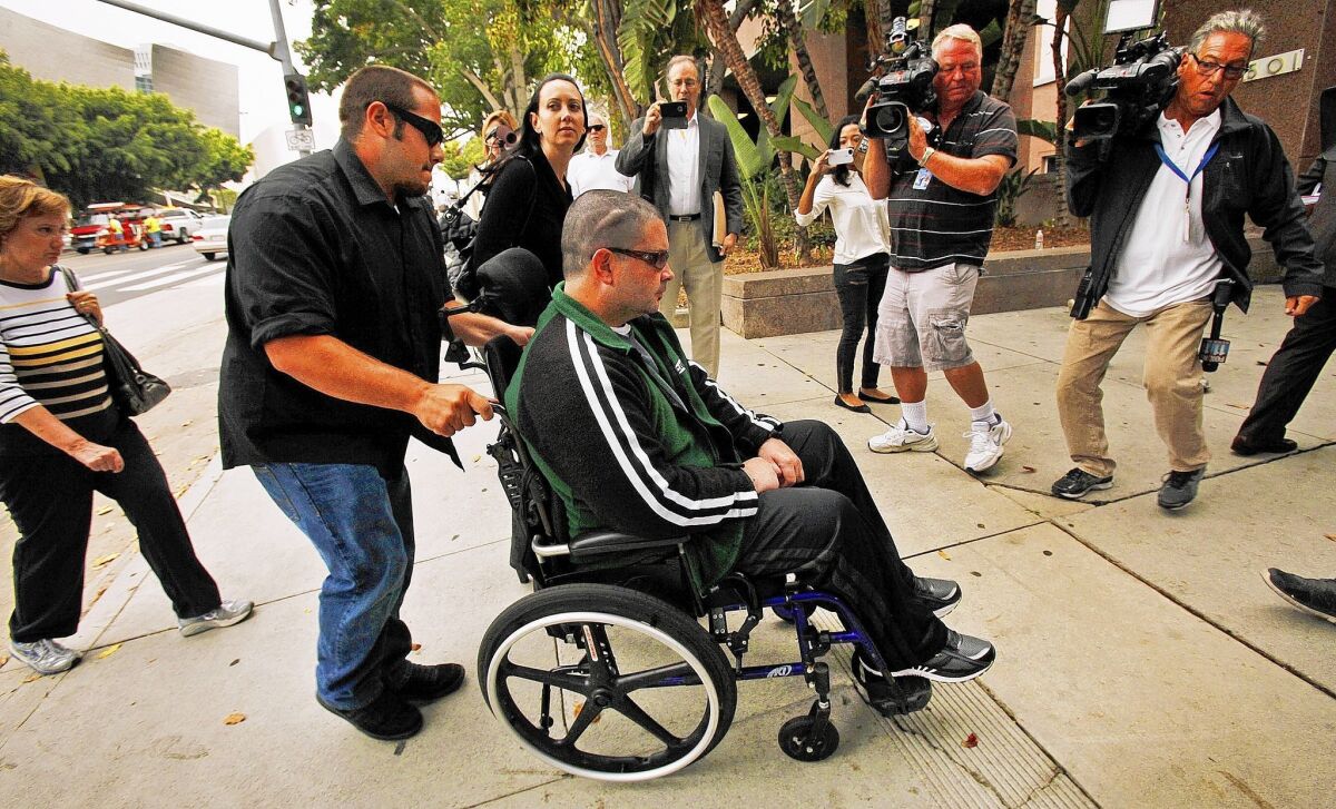 A wheelchair-bound Bryan Stow is surrounded by his mother, sister and media as he is led into the courthouse in downtown L.A. on Wednesday.