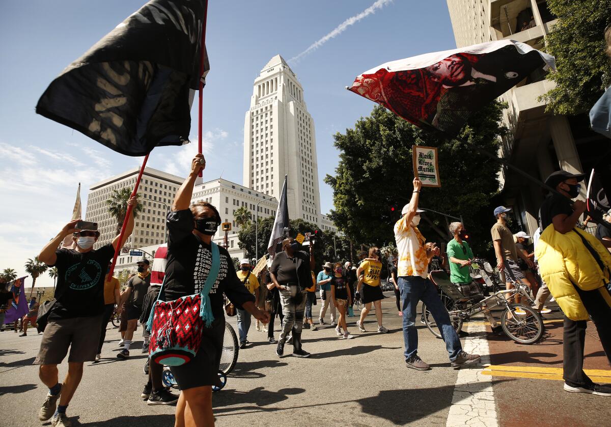 Protesters march past Los Angeles City Hall on Spring Street following a Black Lives Matter rally for George Floyd.