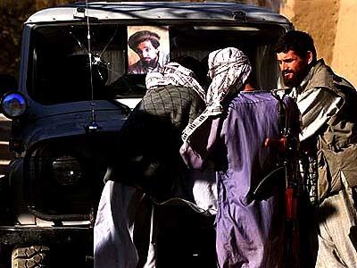 Northern Alliance soldiers gather next to a military jeep. All military vehicles carry a portrait of Ahmed Shah Massoud, the Alliance's former commander.