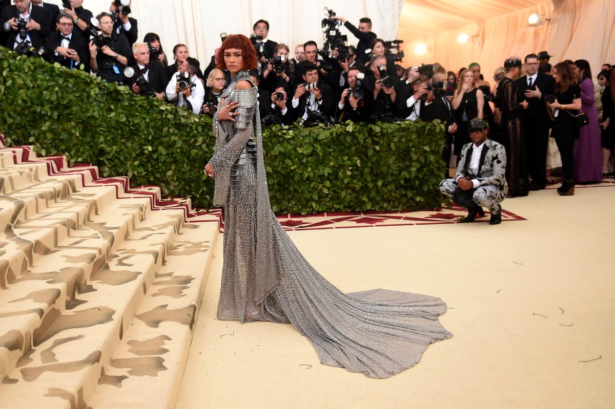 Zendaya poses at the bottom of the steps of the Metropolitan Museum of Art in a long, chainlink gown. 