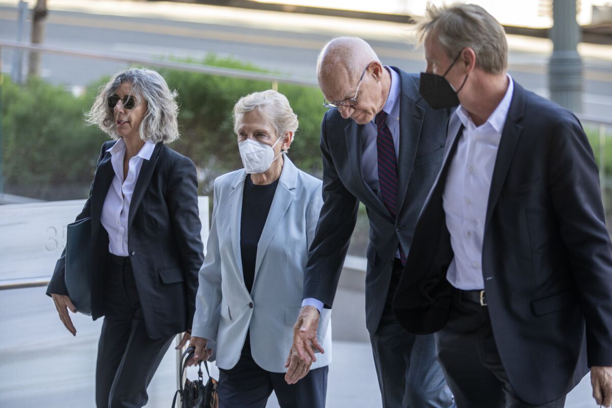 Marilyn Flynn, 83, wearing a face mask and gray jacket, walks into the U.S. District Courthouse in downtown L.A.