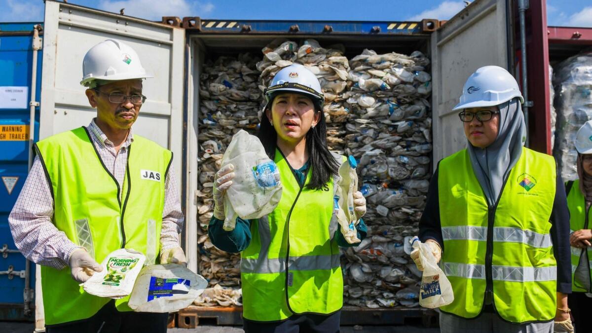 Malaysian Environment Minister Yeo Bee Yin, center, shows samples of plastic waste shipped from Australia at a port west of Kuala Lumpur.