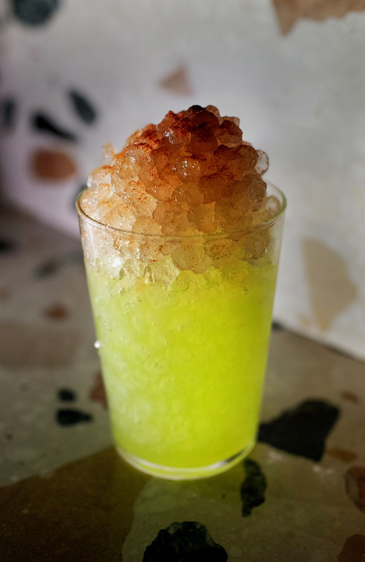 A neon-colored cocktail filled with crushed ice.