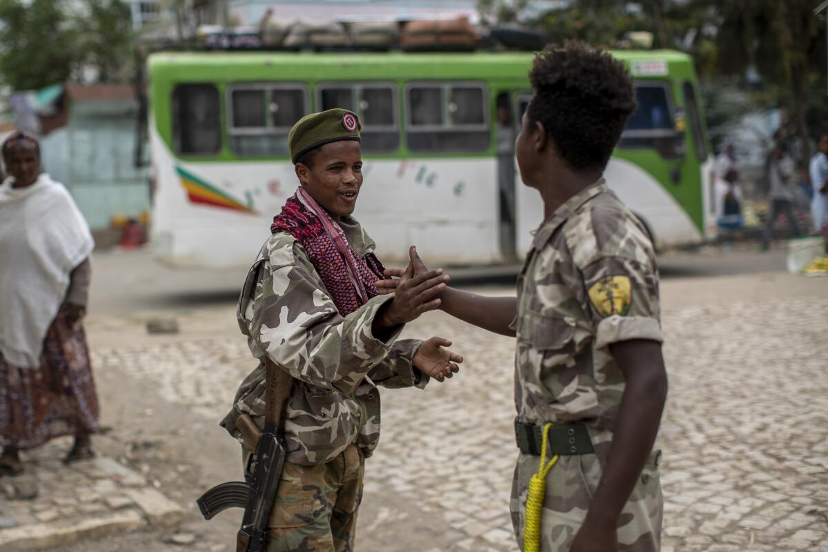 FILE - In this Friday, May 7, 2021 file photo, fighters loyal to the Tigray People's Liberation Front (TPLF) greet each other on the street in the town of Hawzen, then-controlled by the group but later re-taken by government forces, in the Tigray region of northern Ethiopia. The Tigray forces that in late June 2021 have retaken key areas after fierce fighting have rejected the cease-fire and vowed to chase out Ethiopian government forces and those of neighboring Eritrea. (AP Photo/Ben Curtis, File)