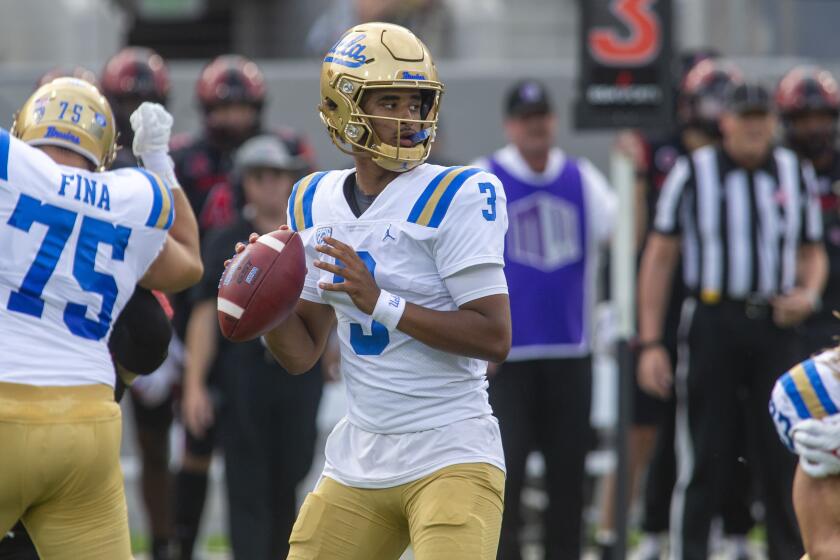 UCLA quarterback Dante Moore looks for a receiver while his teammates block San Diego State players
