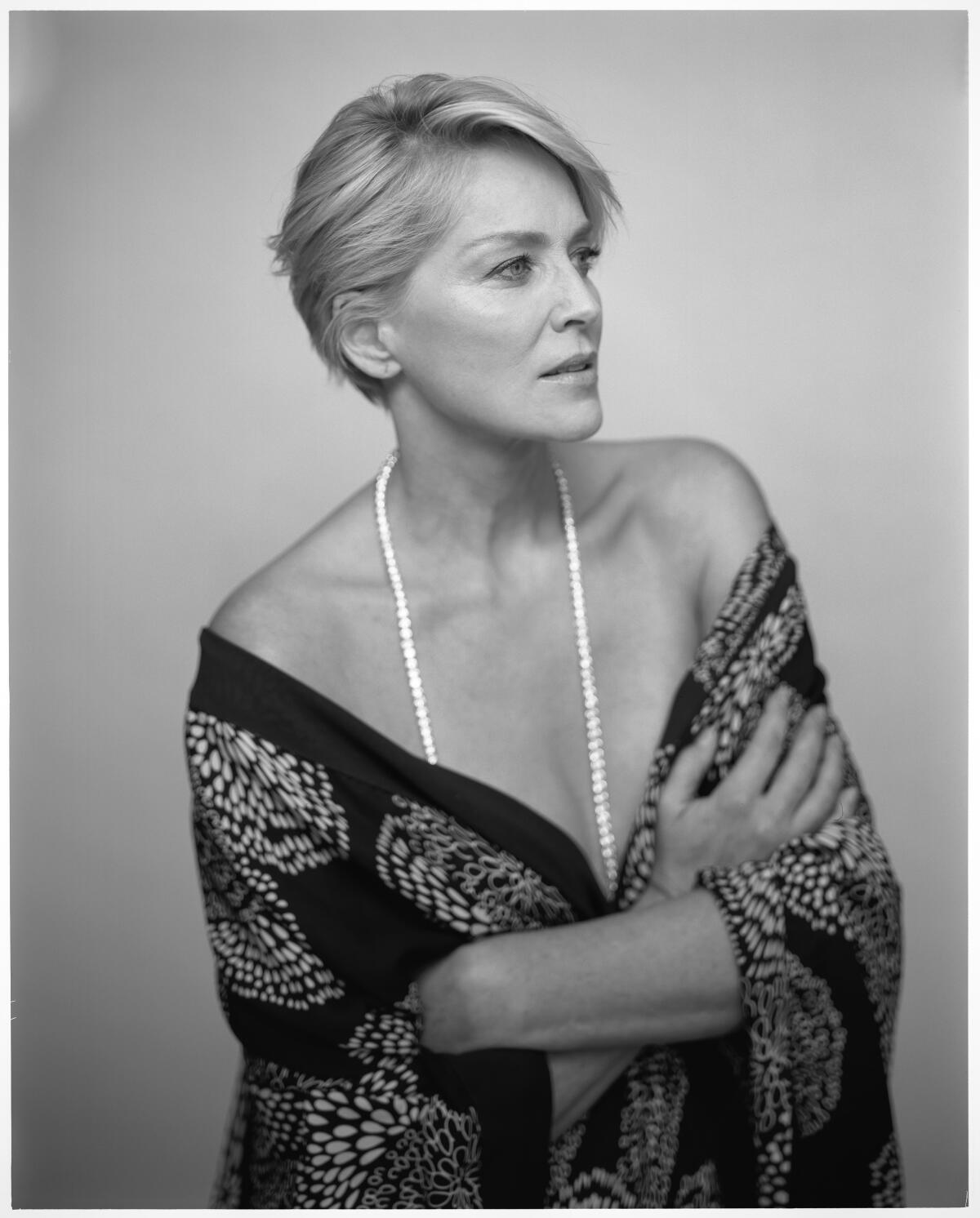 A large-format, black-and-white photo of actor Sharon Stone, waist up, looking pensive