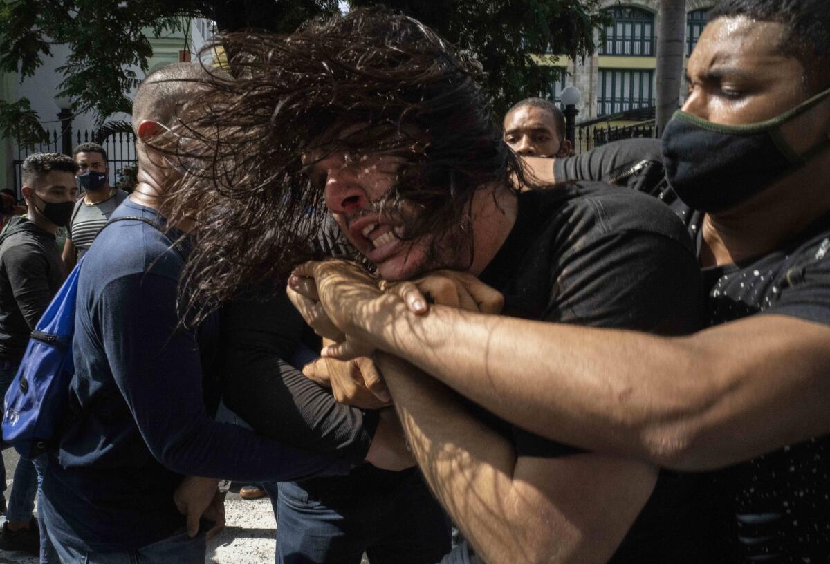 Plainclothes police wrap their arms around a struggling protester  