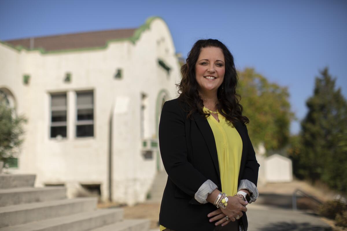 A school official poses outside a school building.