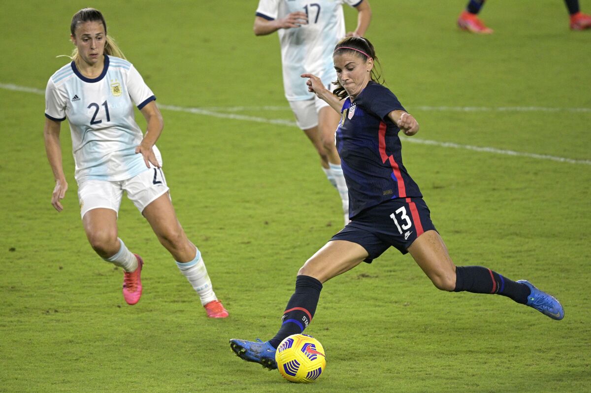 U.S. forward Alex Morgan (13) attempts a shot on goal in front of Argentina defender Adriana Sachs (21).