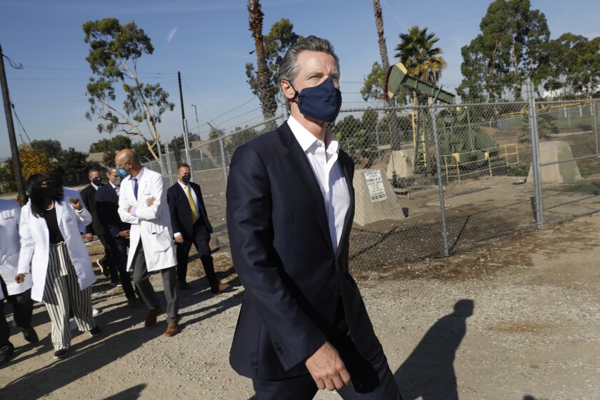 California Gov. Gavin Newsom walks outdoors with people following him