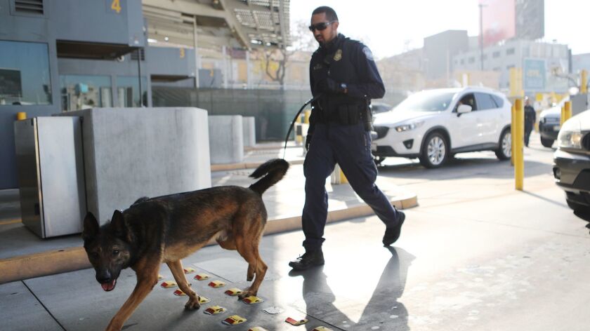 A Customs and Border Protection officer and dog walk to inspect vehicles entering California at the San Ysidro Port of Entry in April.