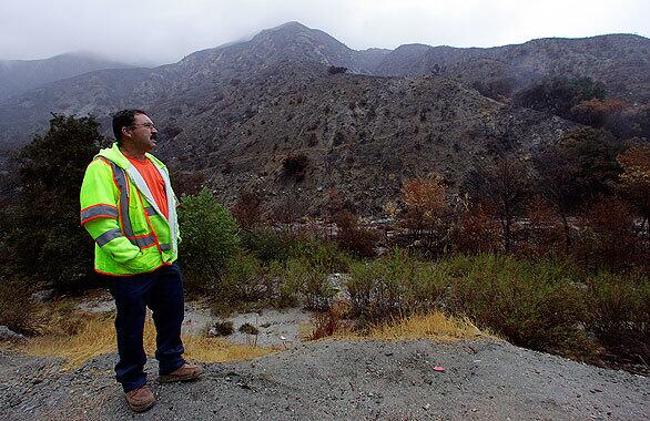 Abel Ballesteros takes a break from working overnight clearing small rock slides along Big Tujunga Canyon Road. Residents of hillside homes braced for possible flash floods and mudslides. Only a few rock slides along occurred along the road as a Pacific storm dampened foothill areas devastated by wildfires.