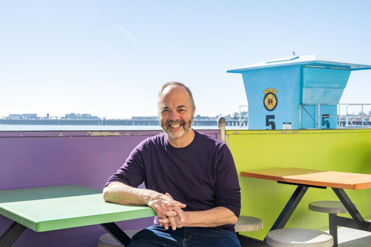 Ken Doctor sits at a table near the beach.