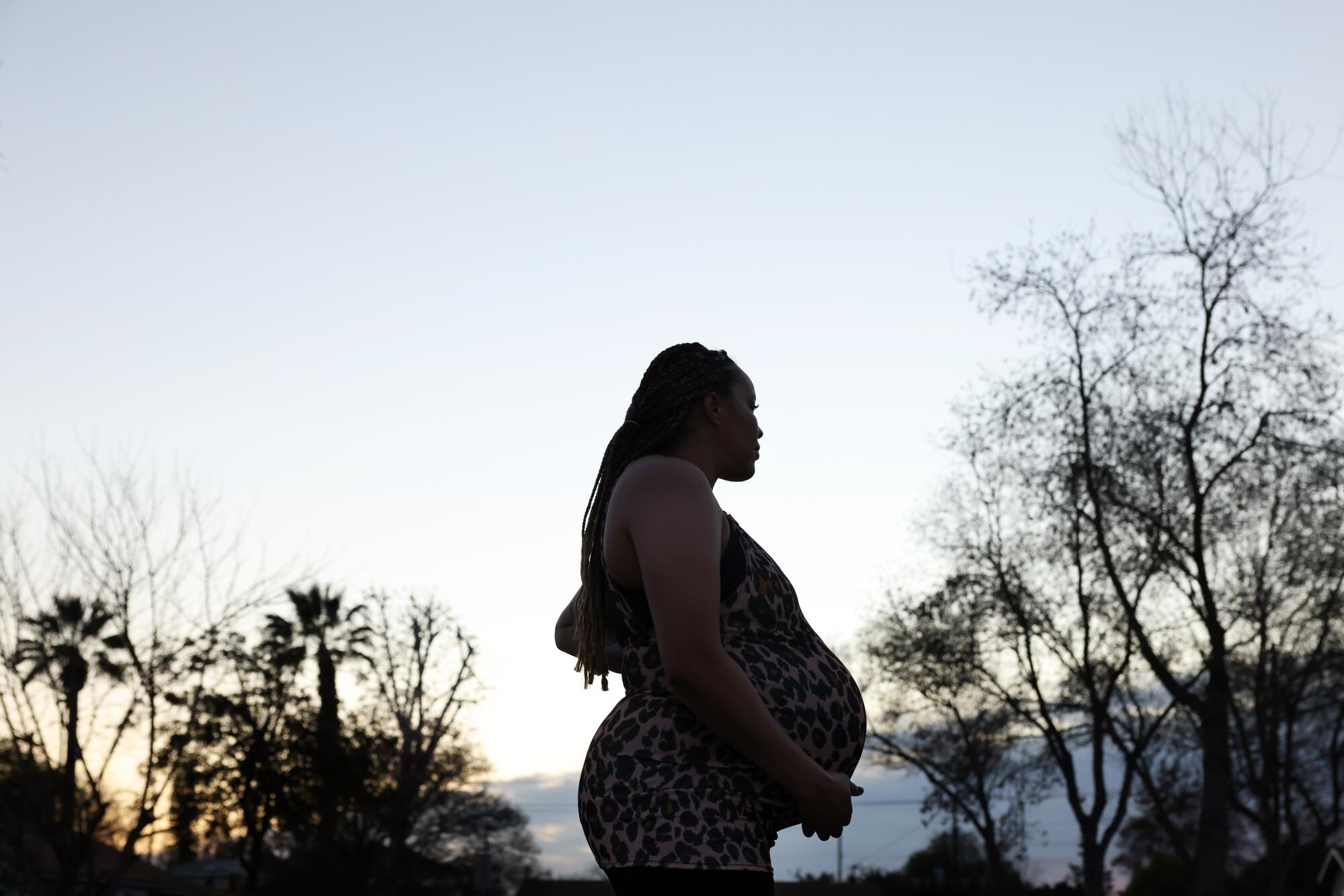 A pregnant woman goes for a walk in the twilight.