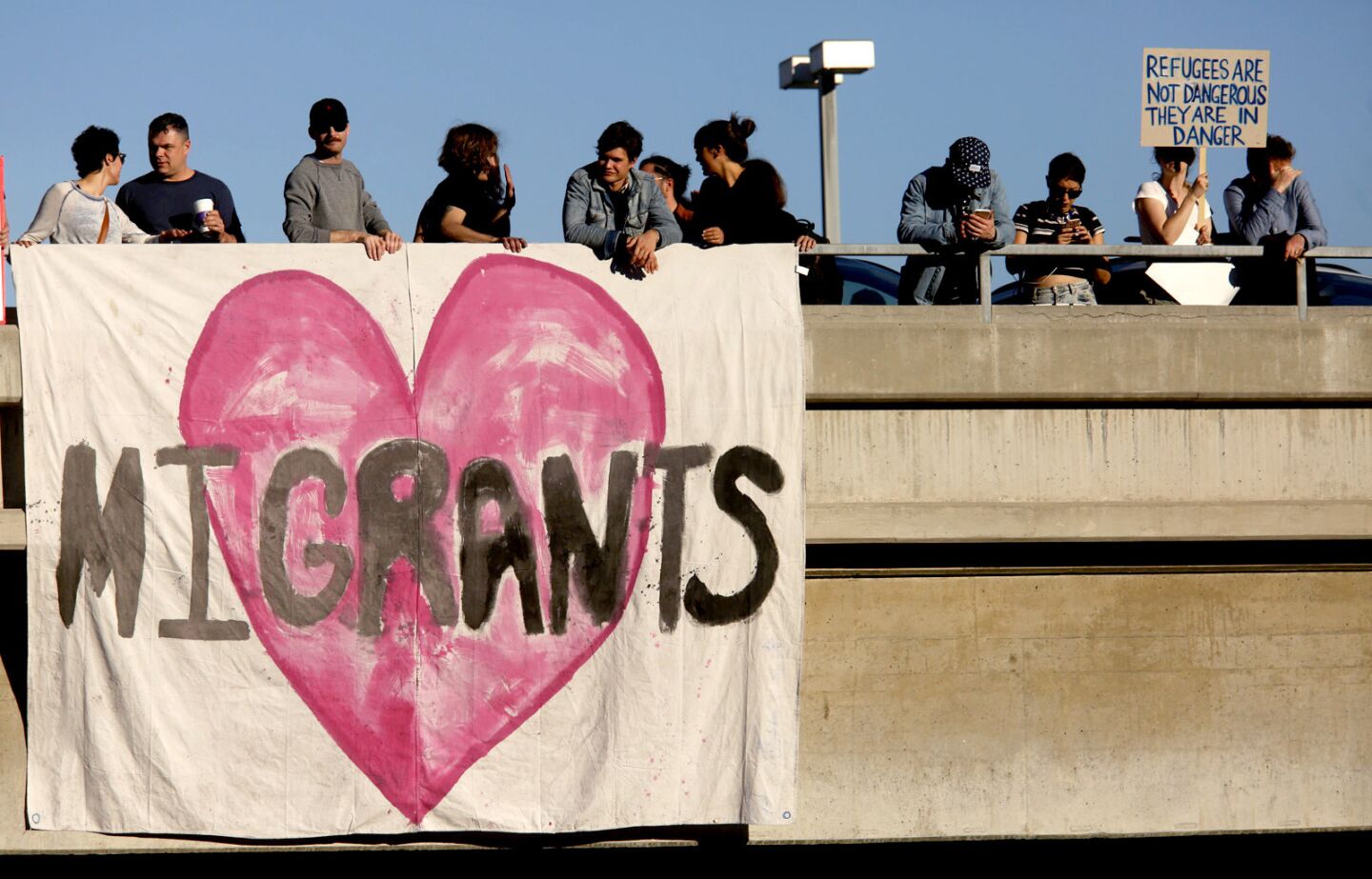 People hang a banner in support of immigrants on a parking structure across the street from the Tom Bradley International Terminal at LAX.