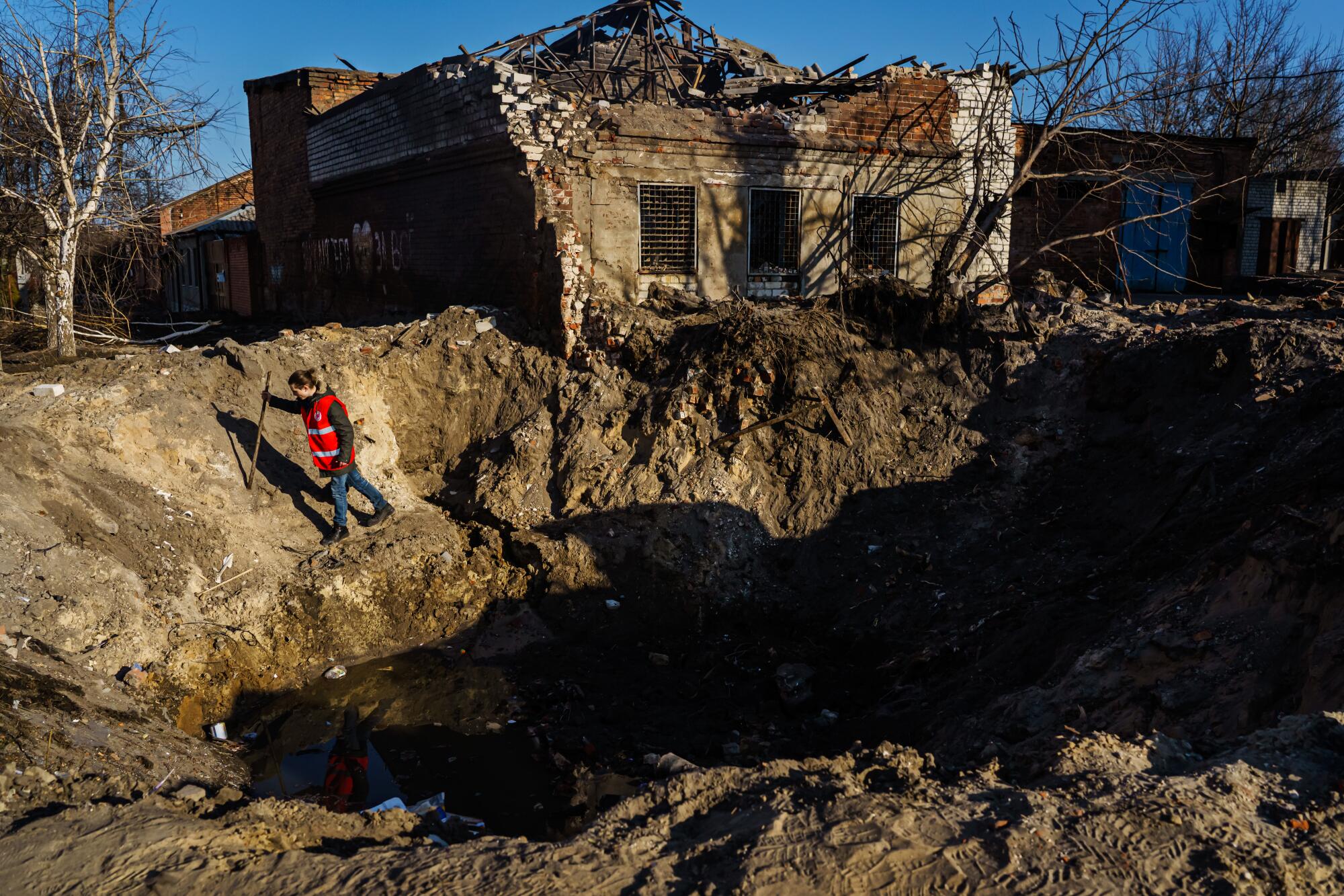A Red Cross worker examines a crater caused by bombing in Kharkiv.