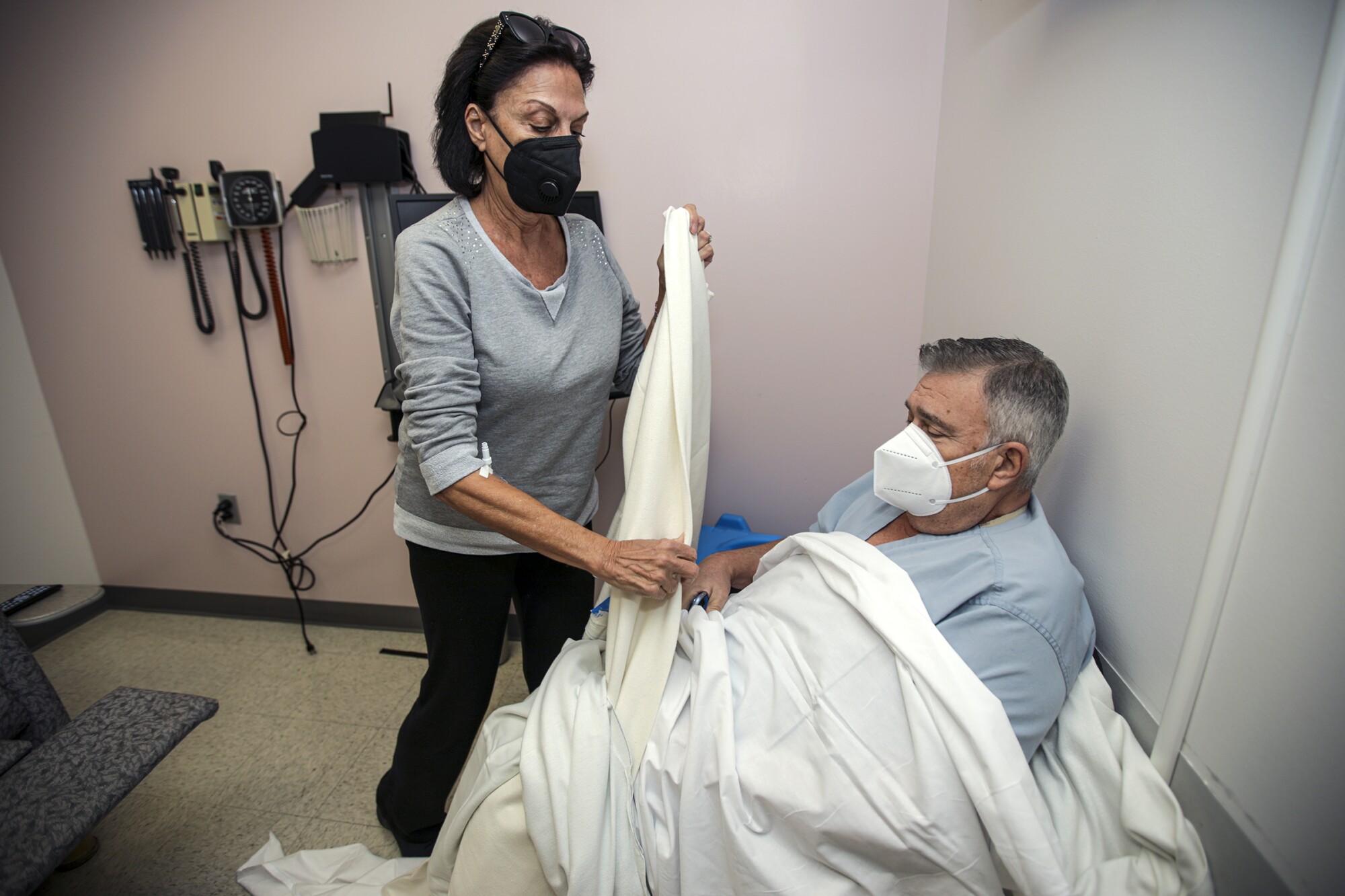 Sima Fischl covers husband Peter with a blanket in a hospital room 