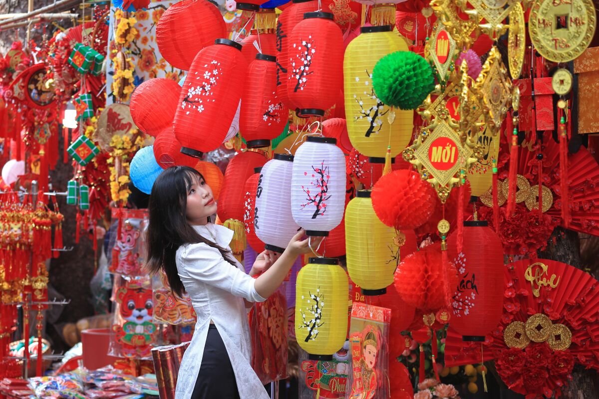 Woman looking at lanterns during traditional Chinese New Year "Tet" Market in the old quarter of Hanoi, Vietnam.