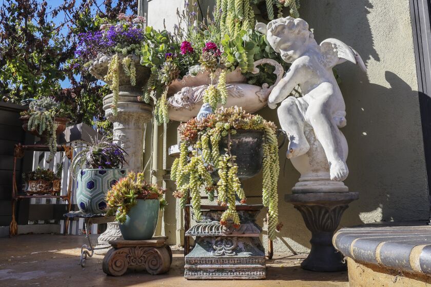 The garden brims with antique religious art and colorful potted plants 