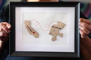 A person holds a framed piece of art showing the states of California and Zacatecas