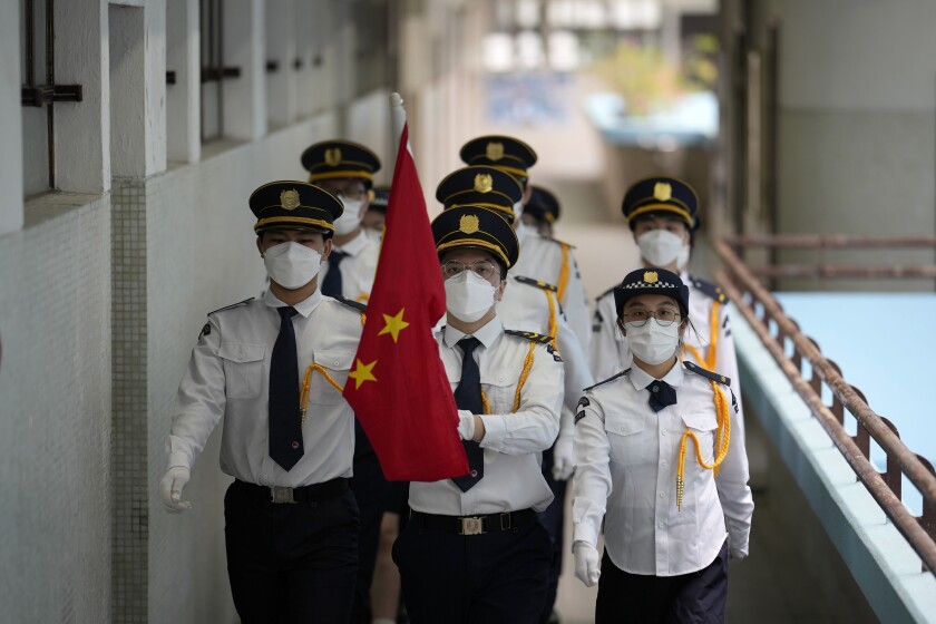 Estudiantes uniformados que llevan la bandera china