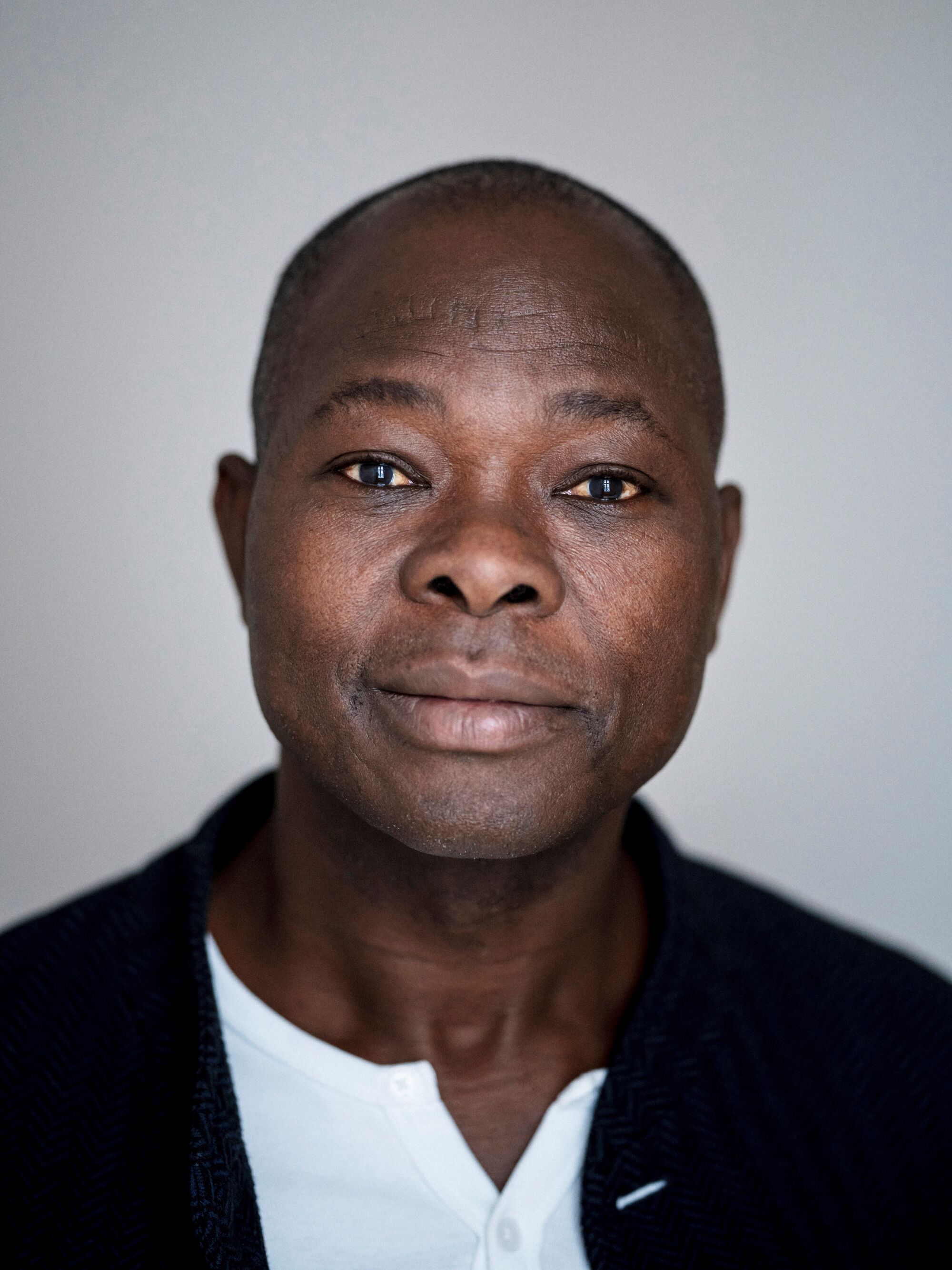 Francis Kéré, wearing a white shirt and dark jacket, in a portrait.