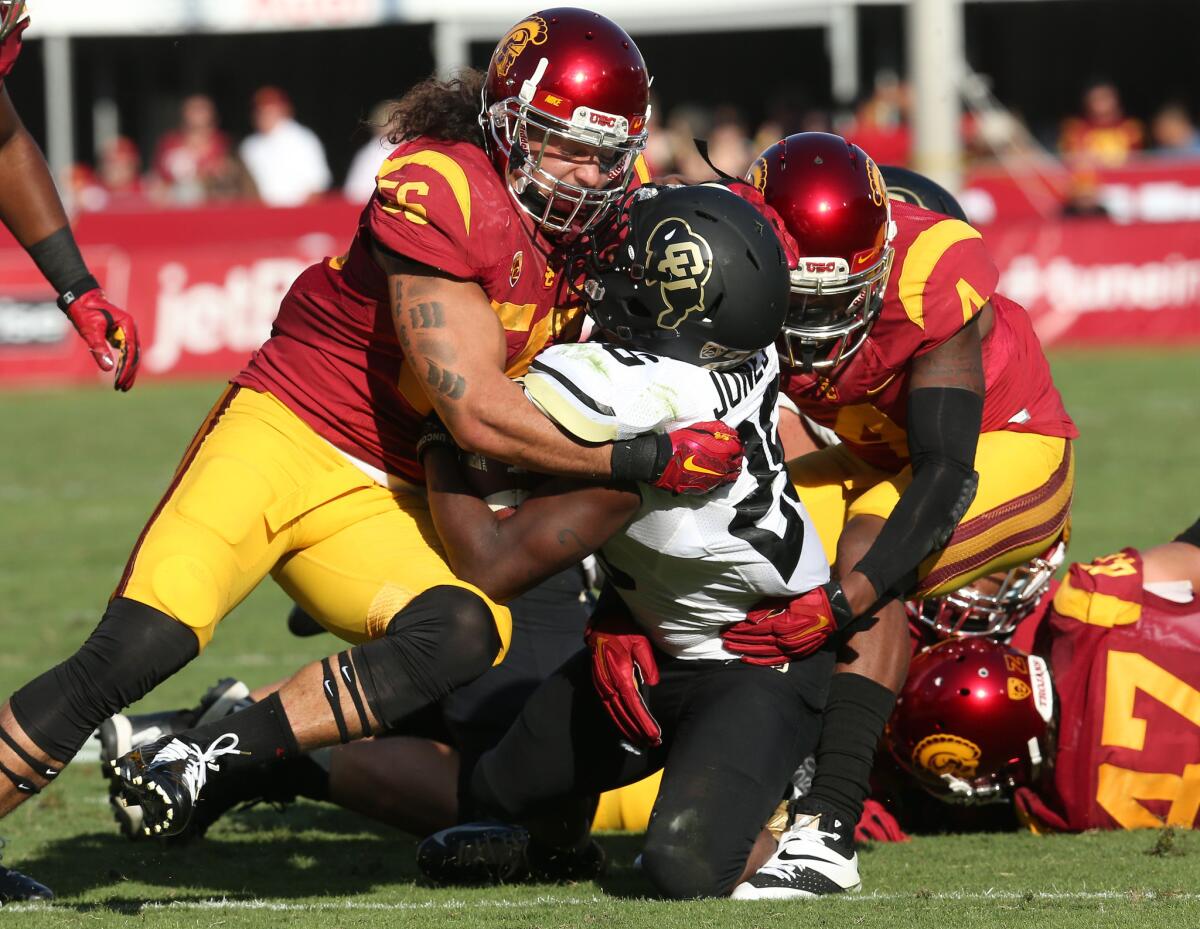 USC's Anthony Sarao, left, and Chris Hawkins stop Colorado running back Tony Jones on Saturday at the Coliseum.