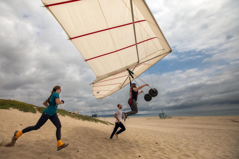 Playa Del Rey,, CA - June 11: Kim Wright, left, and gliding instructor Adam Zachary Smith, middle, help students hang glide off the bluff on Sunday, June 11, 2023, at Dockweiler Beach in Playa Del Rey, CA. (Francine Orr / Los Angeles Times)